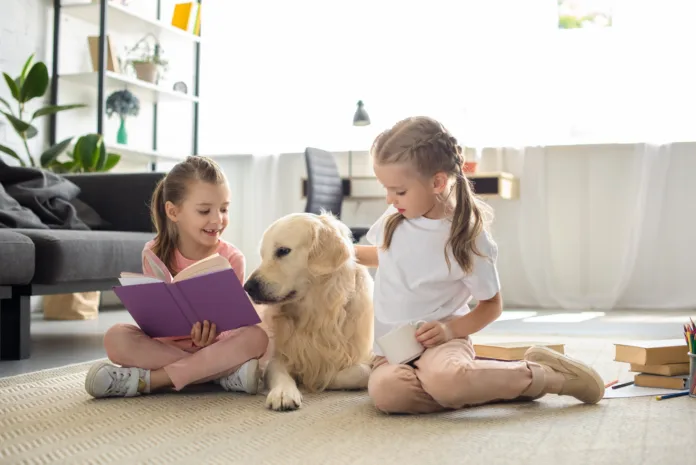 Two children reading with a Golden Retriever at home Two children reading with a Golden Retriever at home